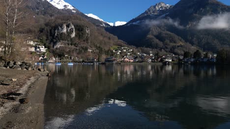 Toma-Aérea-De-Un-Pequeño-Pueblo-Situado-Bajo-Los-Alpes-En-Walensee,-Suiza.