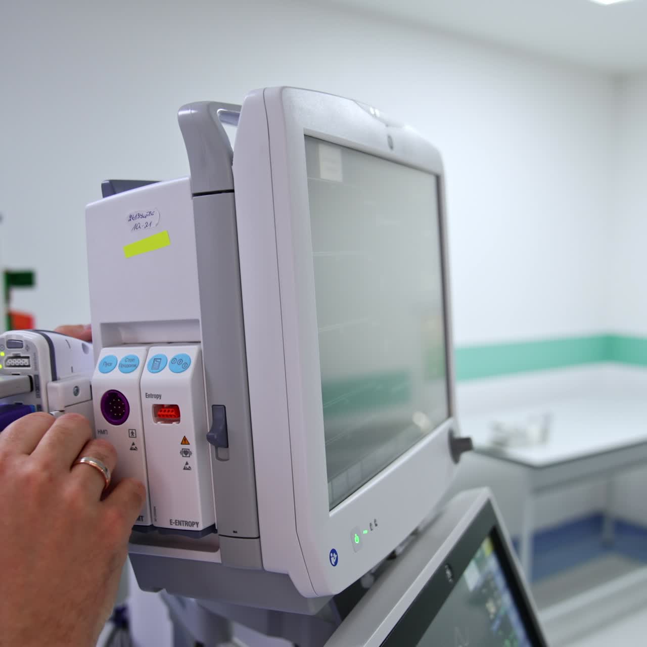 Male hands hold the screens of a lung ventilator in surgery room. Man disconnects the part of appliance from behind the monitor