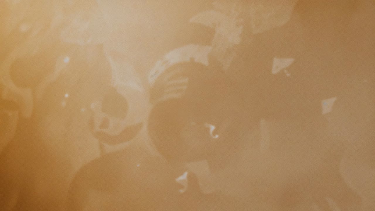 Expanding central black dot forming spiky disk on tan tray, including ringed and smaller disks