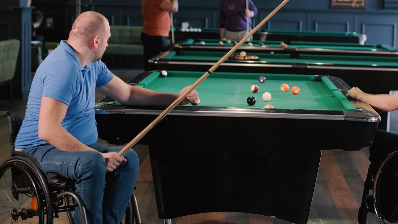 Volwassen mannen met een handicap in een rolstoel spelen biljart in de club
