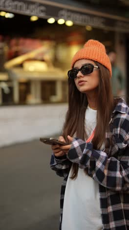 woman in fashionable urban outfit using a smartphone