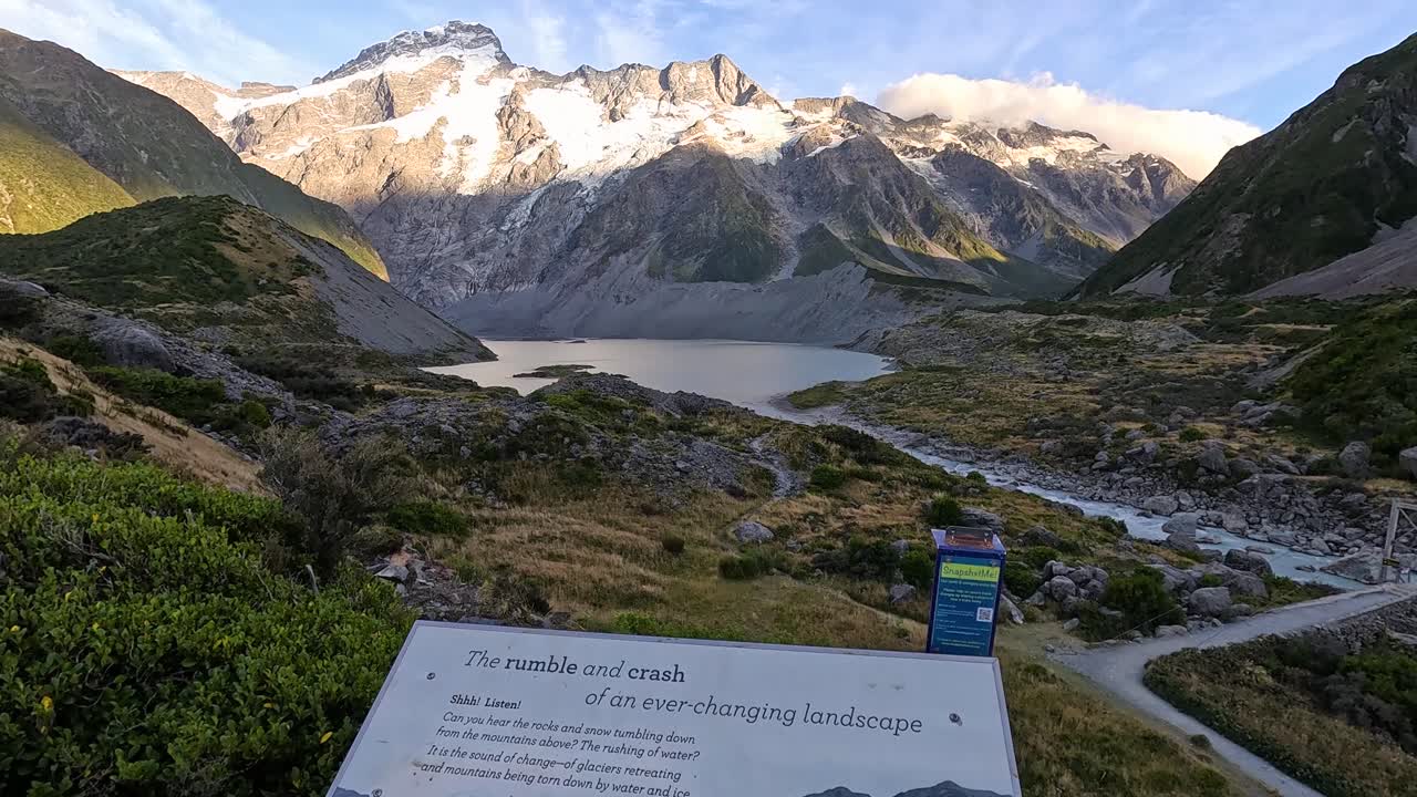 Panning up from an information board to reveal a dramatic mountain range along the Hooker Valley track around Aoraki - Mt Cook in New Zealand's South Island