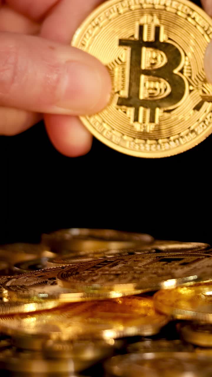 Duas mãos puxam uma moeda de criptomoeda dourada acima de uma pilha, com iluminação dramática e perspectiva macro.