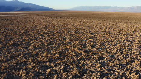 backward moving aerial over devils golf course having rugged and harsh terrain formed by large salt pan on floor of death valley national park