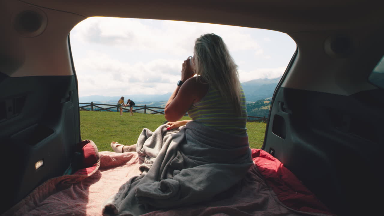 Woman relaxing in car's back seat with a view of the mountains