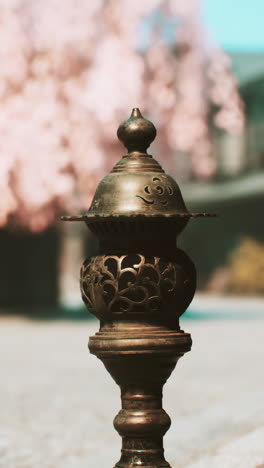 bronze lantern in a japanese garden with cherry blossoms in the background