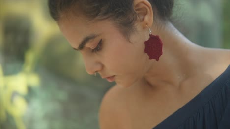 a shot of an indian woman wearing a back slit with unique woven earrings, left side view