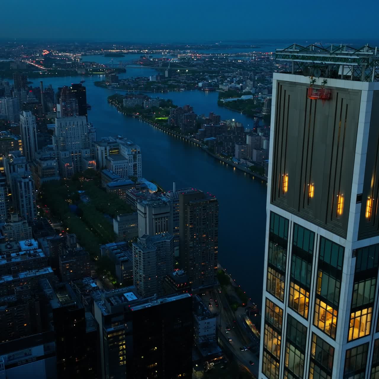 New York in lights at evening time. Drone footage over the city near the huge skyscraper building