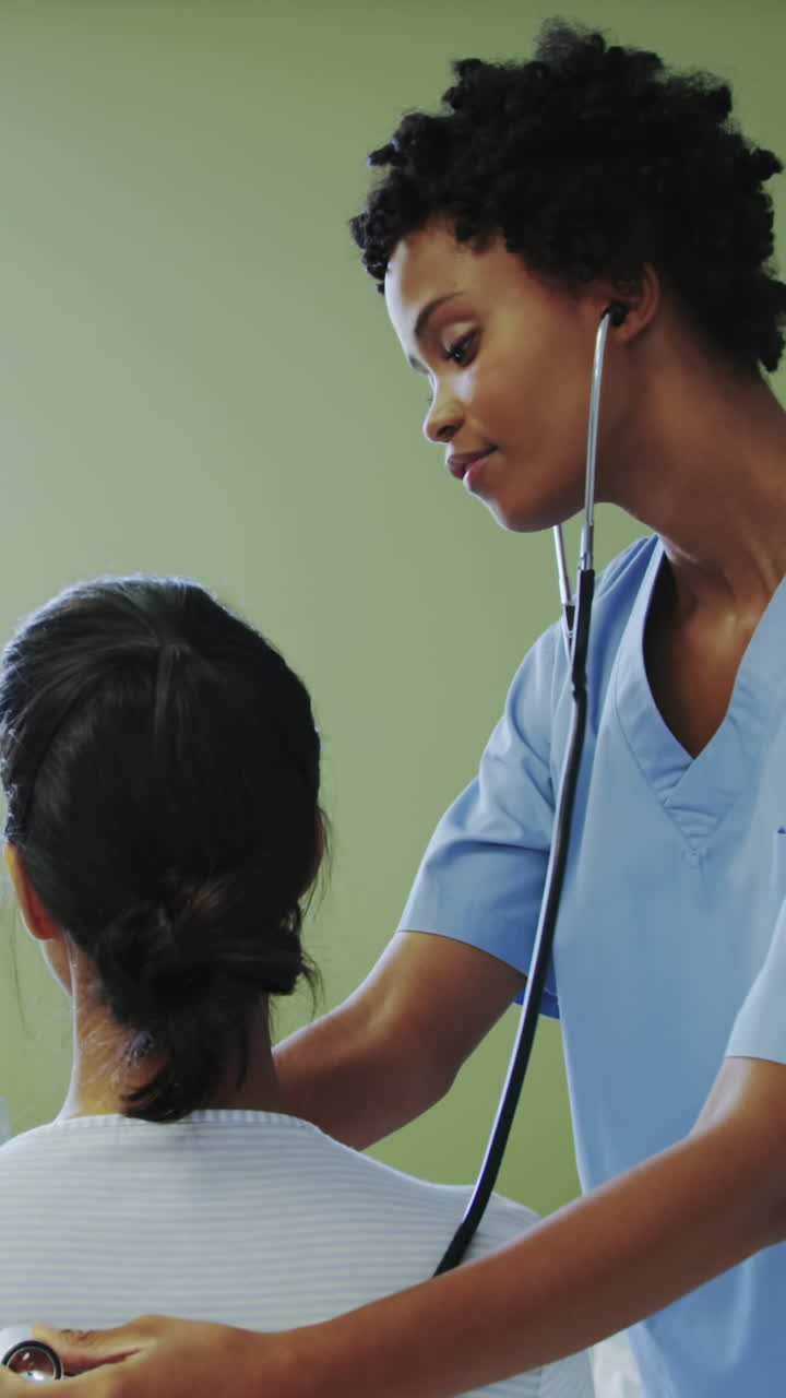 Side view of African american female doctor examining female patient in the ward at hospital