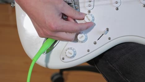 un disparo medio de un hombre tocando solos de guitarra, acordes y ritmo con el bajo en un estudio centrándose en las manos