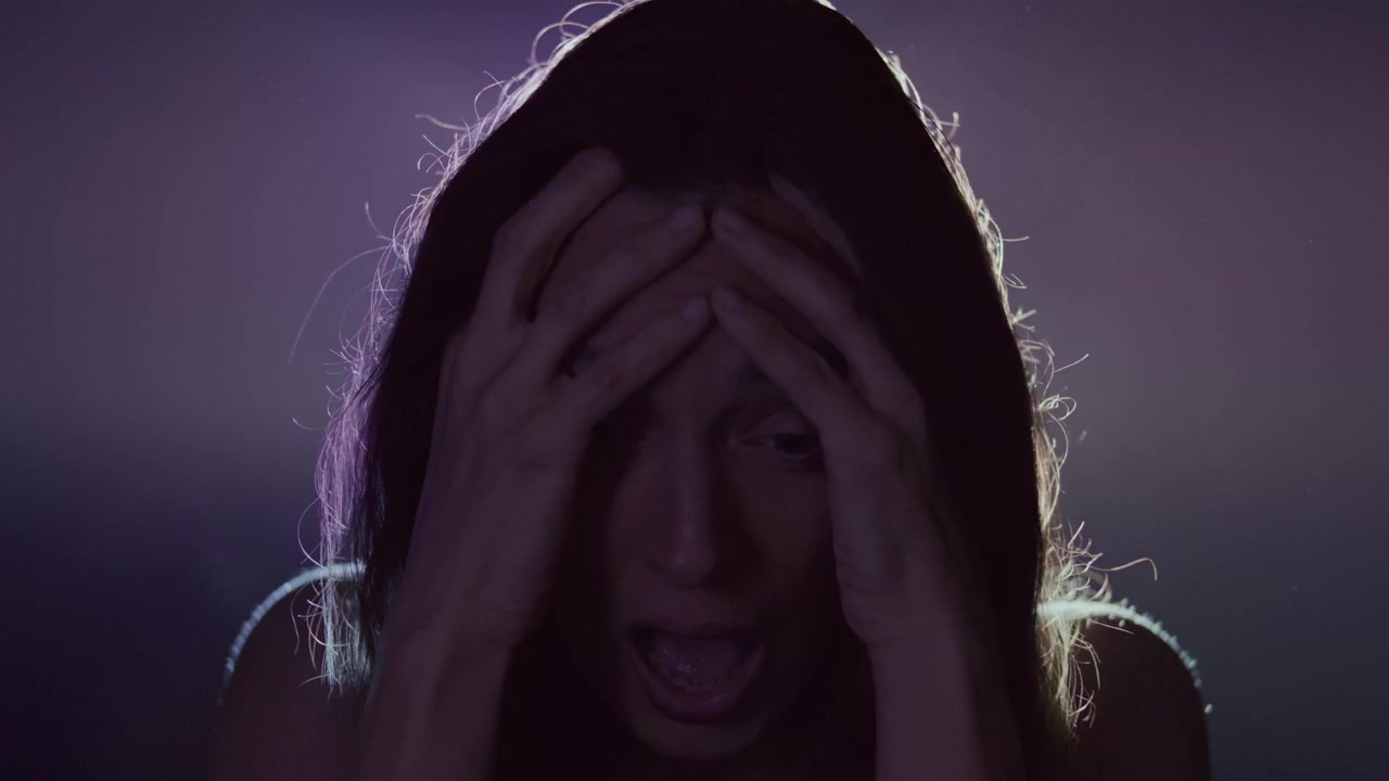 Donna che si tiene la testa e grida durante un attacco di panico sotto illuminazione al neon
