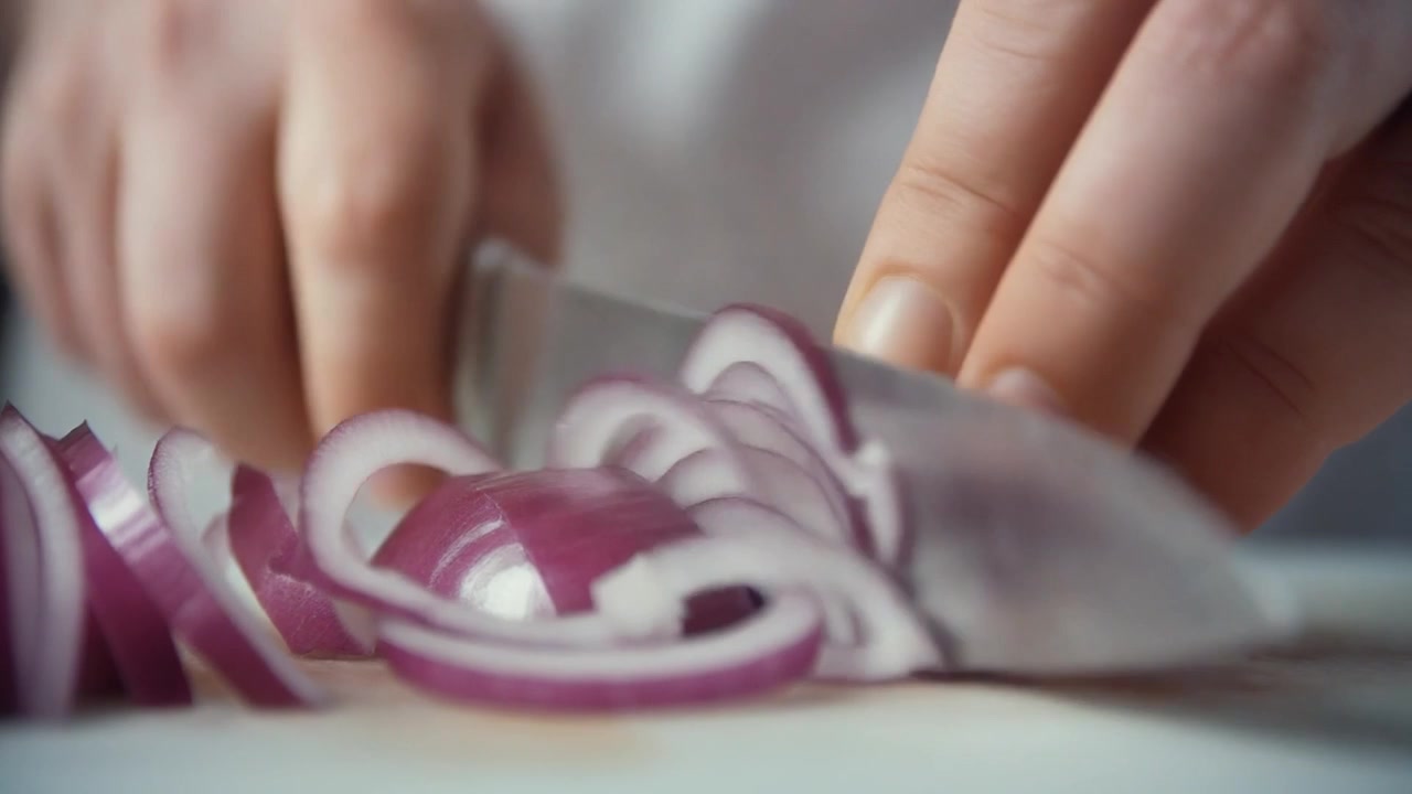 Chef Slicing Fresh Red Onion on Cutting Board