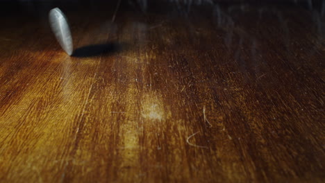 Closeup-of-Irish-coin-penny-flipping-on-wooden-table,-static,-slow