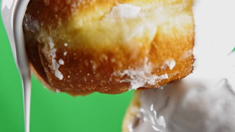 dripping white frosting on a doughnut