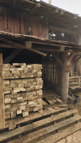 viejo edificio de madera con una pila de madera delante de él