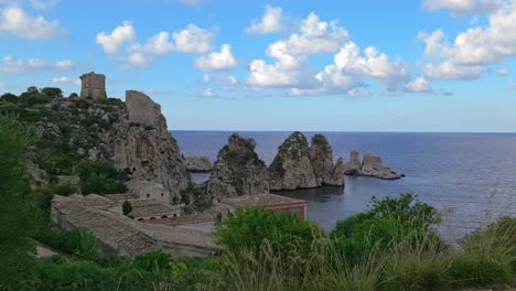 zoom in on stacks or faraglioni of scopello in background, sicily