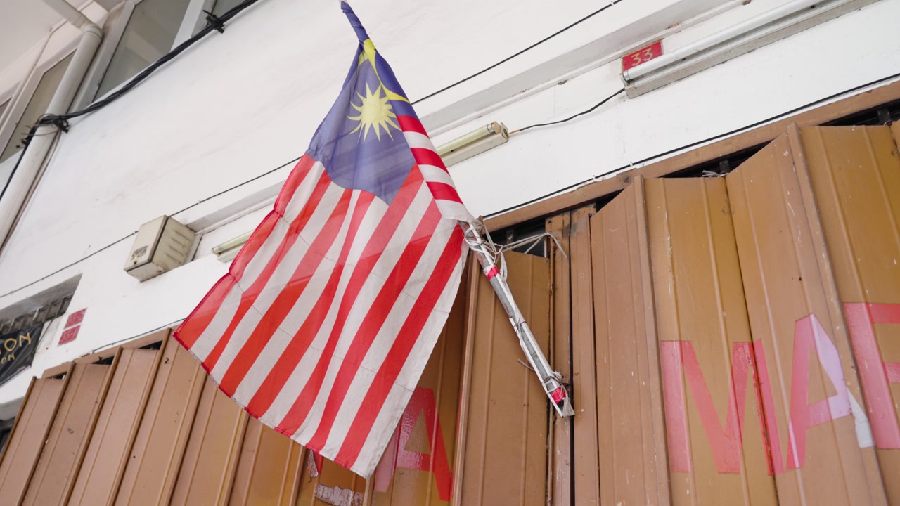 The Malaysian flag is waving outside a building in daylight. Patriotic atmosphere symbolizing national identity, pride, independence, and cultural heritage in Southeast Asia.