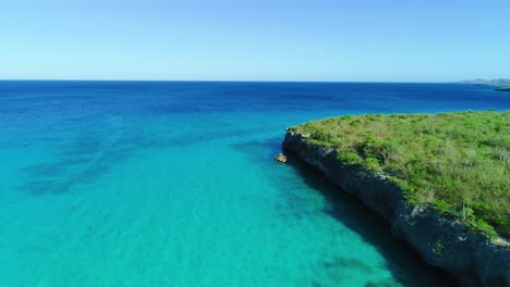 Las-Tranquilas-Ondas-De-La-Corriente-Empujan-Contra-Acantilados-Rocosos-Y-áridos,-Aguas-Profundas-Y-Azules-Del-Caribe.