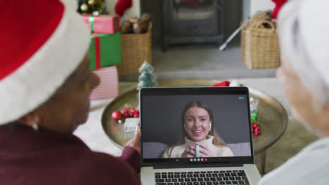 Diverse-senior-female-friends-using-laptop-for-christmas-video-call-with-happy-woman-on-screen