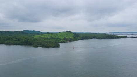 a moody, overcast sky hangs above the lush, jungle-covered banks of the chagres river in panama, where vital shrimp farms are nestled along the historic waterway.