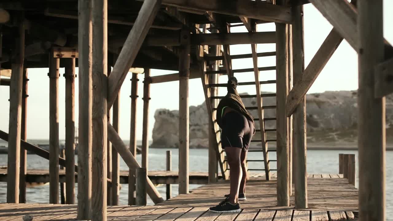 hombre haciendo ejercicios de estiramiento en el paseo marítimo