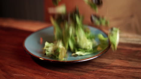tira la ensalada al plato en un restaurante de madera a cámara lenta