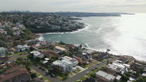 aerial establishing shot of neighborhood homes with ocean view panorama on a bright sunny morning