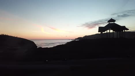 aerial 4k side pan cliff beach setting at sunset, indonesia