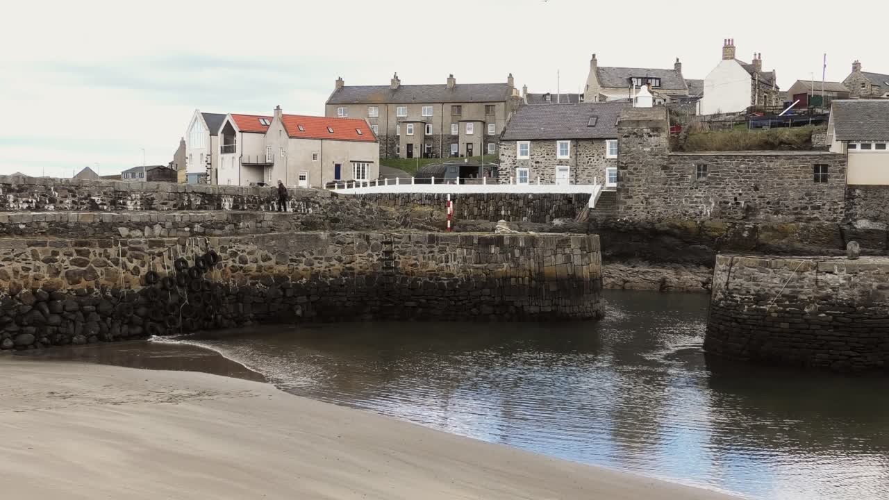 En dame går langs havnemuren i Portsoy Havn