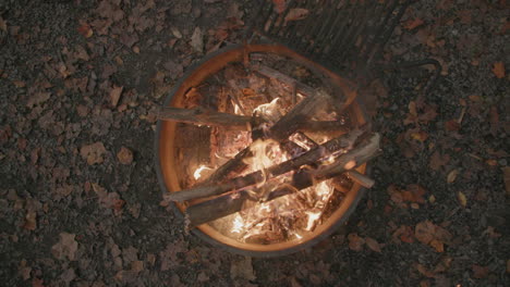 top down slow motion footage of a campfire with embers and sparks flying upward into camera and above