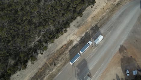 Multi-trailer-cargo-truck-stopping-over-at-checkpoint-for-inspection,-aerial-tracking-shot