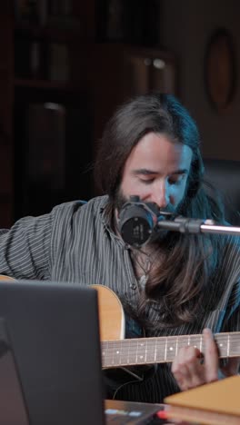 a man playing an acoustic guitar and singing into a microphone