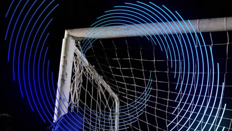 Animation-of-blue-line-spiral-rotating-over-male-football-goalkeeper-saving-goal