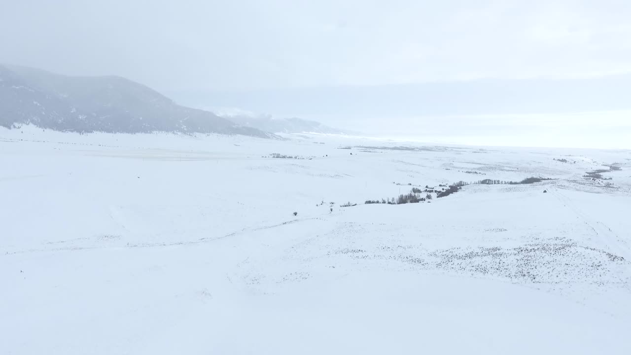 AERIAL - Snow covered valley with mountains in the distance