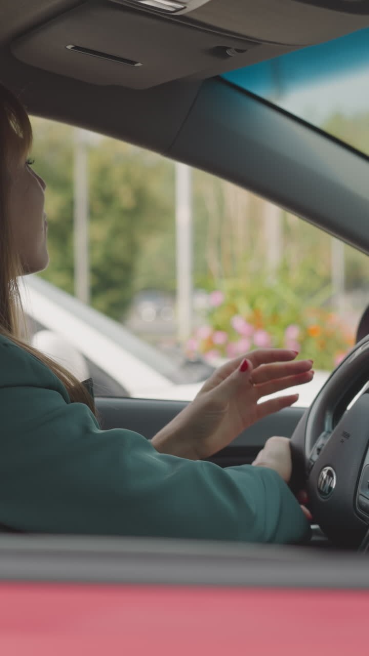 Businesswoman turns steering wheel moving slowly in traffic jam in city center. Young female driver in personal vehicle hurries up to work closeup
