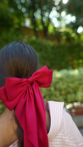 woman with a red bow in her hair in a garden