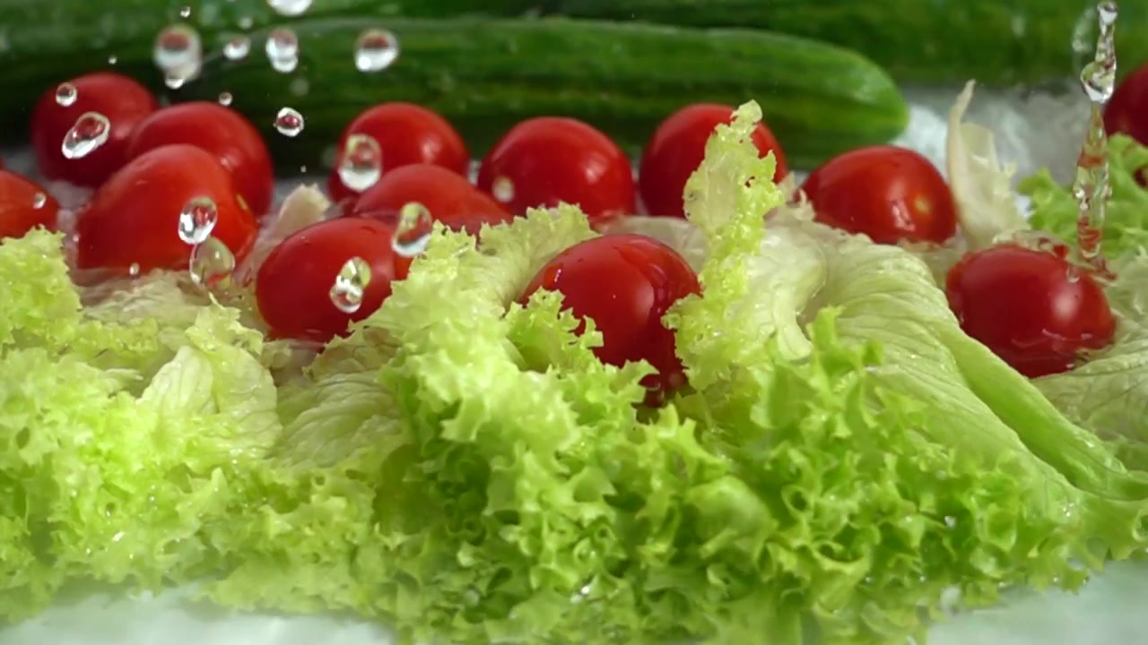 Radish, cucumbers and lettuce leaves in a stream of water. Slow motion.