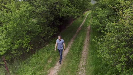 Retreating-drone-shot-of-a-tourist-walking-on-a-dirt-road-in-the-woodlands-of-Tsarichina-Hole-Village-in-a-remote-countryside-in-Bulgaria