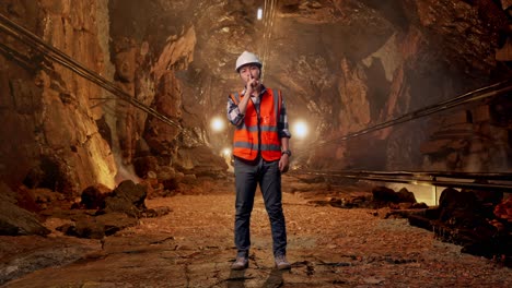 full body of asian male engineer with safety helmet making shh gesture while standing in underground mine tunnel