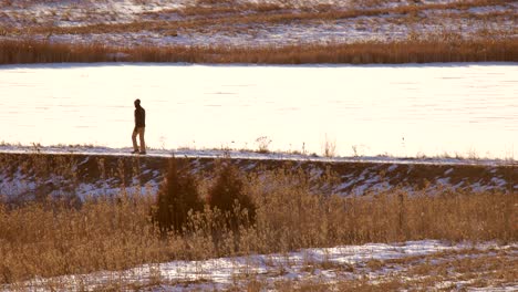 Man-walking-in-a-hiking-trail-in-winter