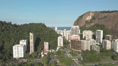 Slow-aerial-movement-forward-and-downward-with-view-of-high-rise-residential-buildings-with-a-mountain-behind-revealing-a-highway-intersection-with-traffic