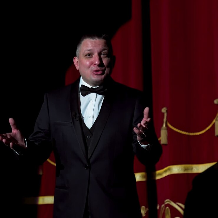 Attore su un palco. Uomo adulto parla al pubblico al microfono o canta canzoni. Tema teatrale