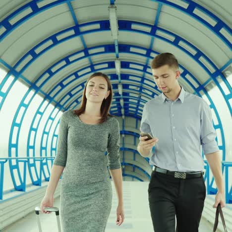 a man and a woman go with luggage at the terminal of the station or airport