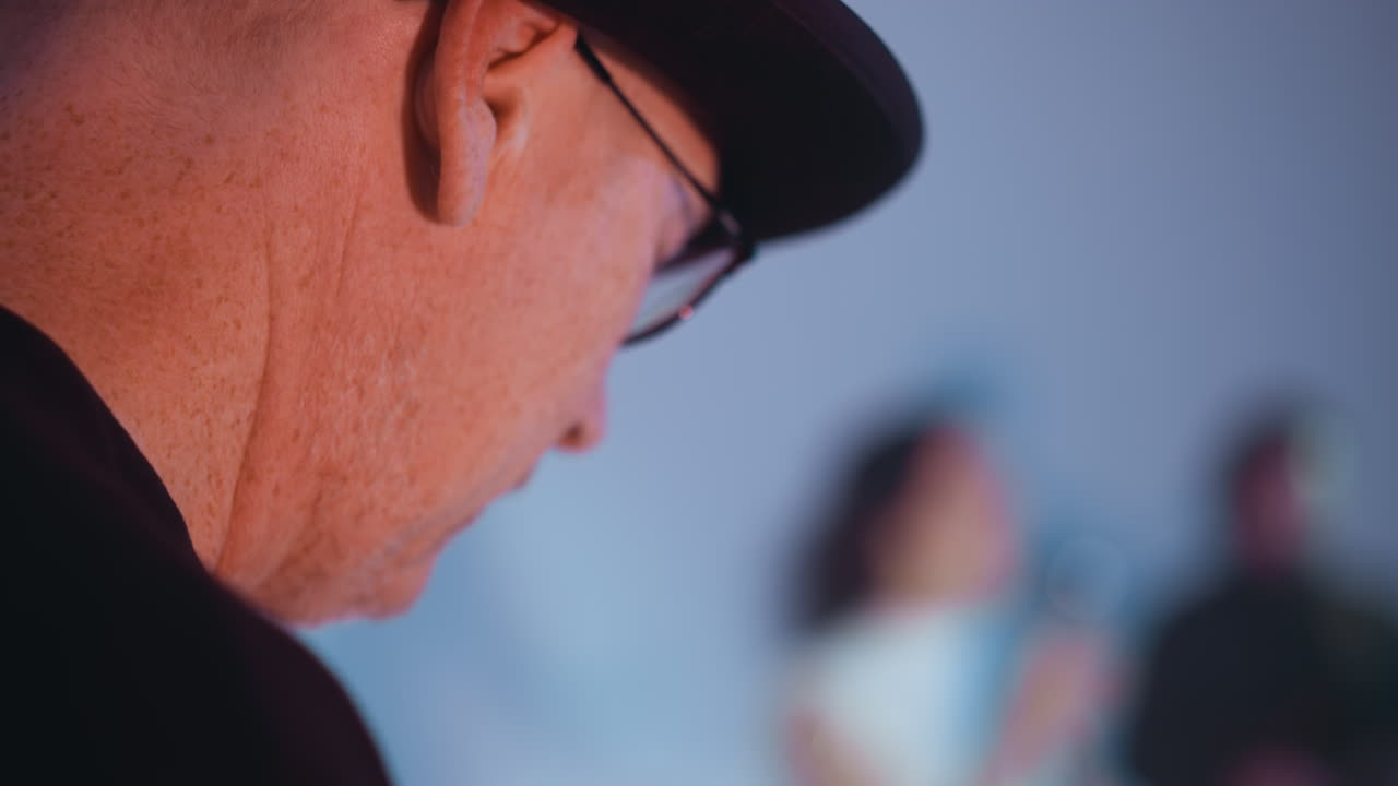 vista perdida del rostro de un hombre con un sombrero negro y gafas con un fondo borroso, mostrando su expresión pensativa