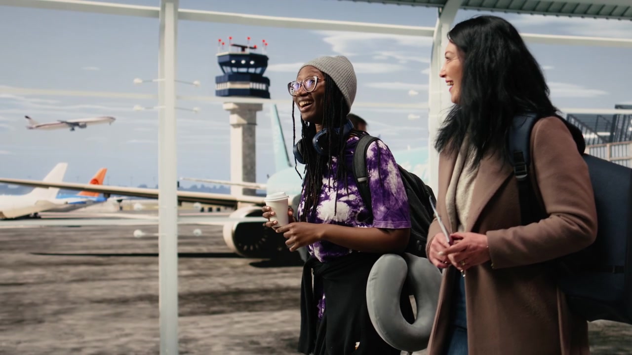Cheerful women walking in airport terminal, laughing, travelling together