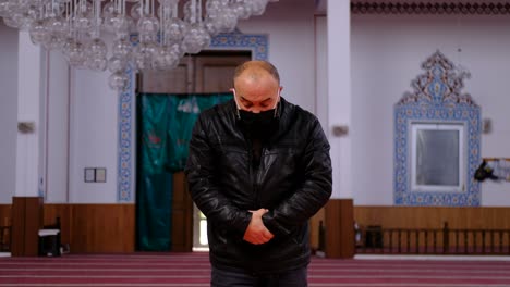 older man prays in a mask in a mosque 1