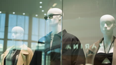 close-up view of male and female mannequins dressed in stylish outfits displayed in a mall. captured with a handheld camera, the video highlights the fashion display and retail environment