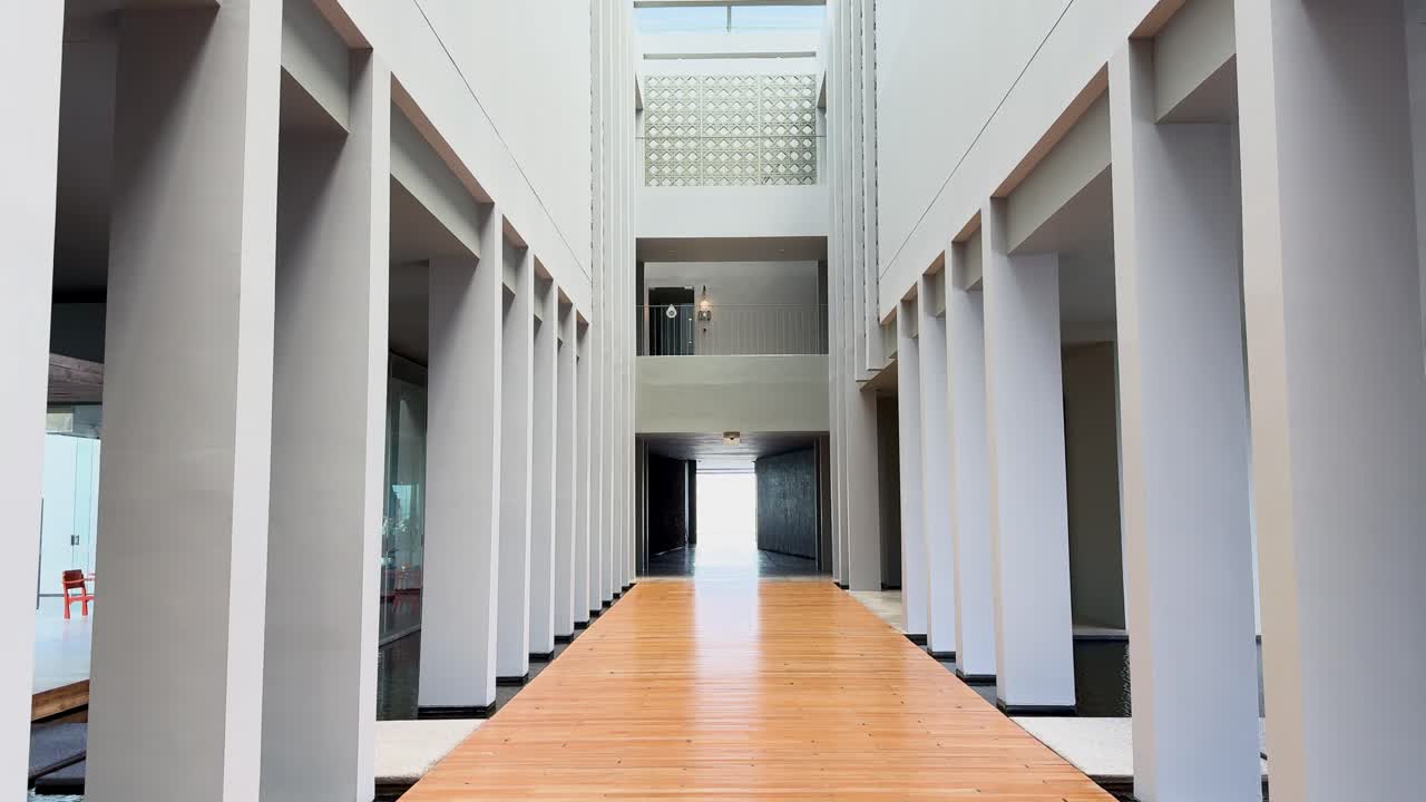 A sleek, modern resort entrance hallway in Phuket, Thailand, featuring tall columns, glass walls, and natural lighting