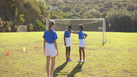 playing soccer, girls in school uniforms celebrating goal on field