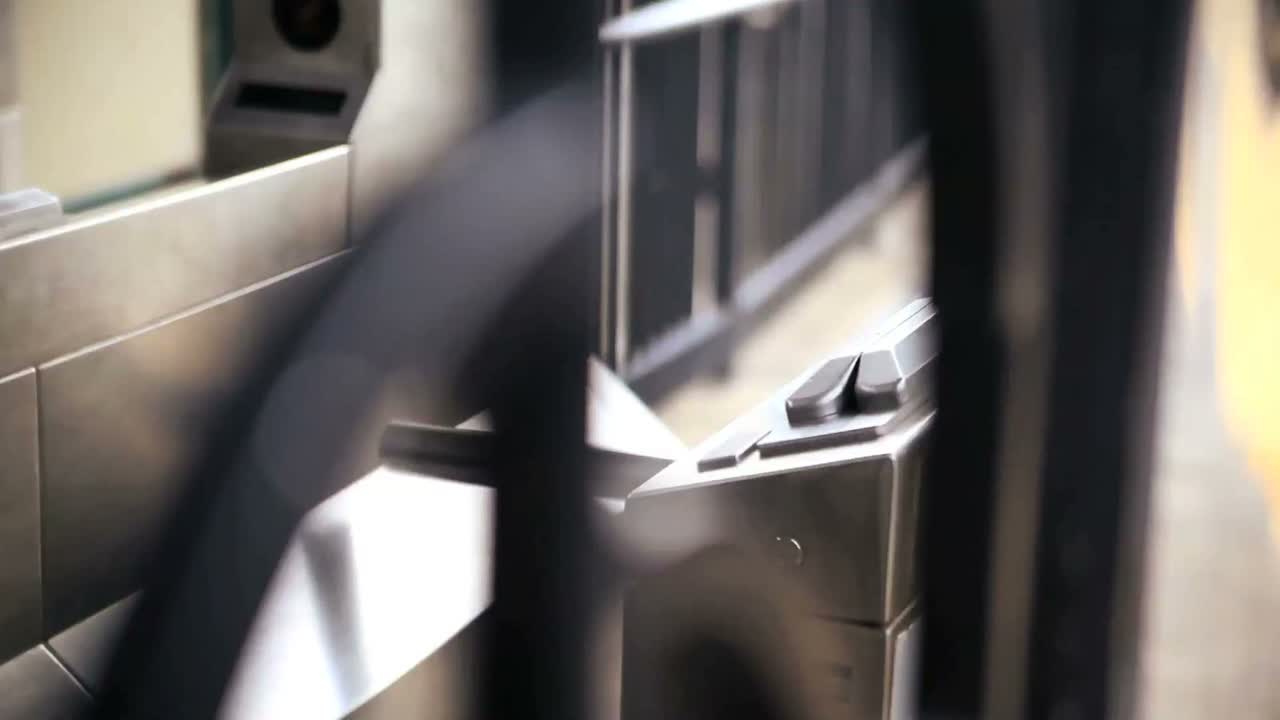 여행자가 카드를 밀고 뉴욕시의 기차역에서 개찰구를 통과합니다.